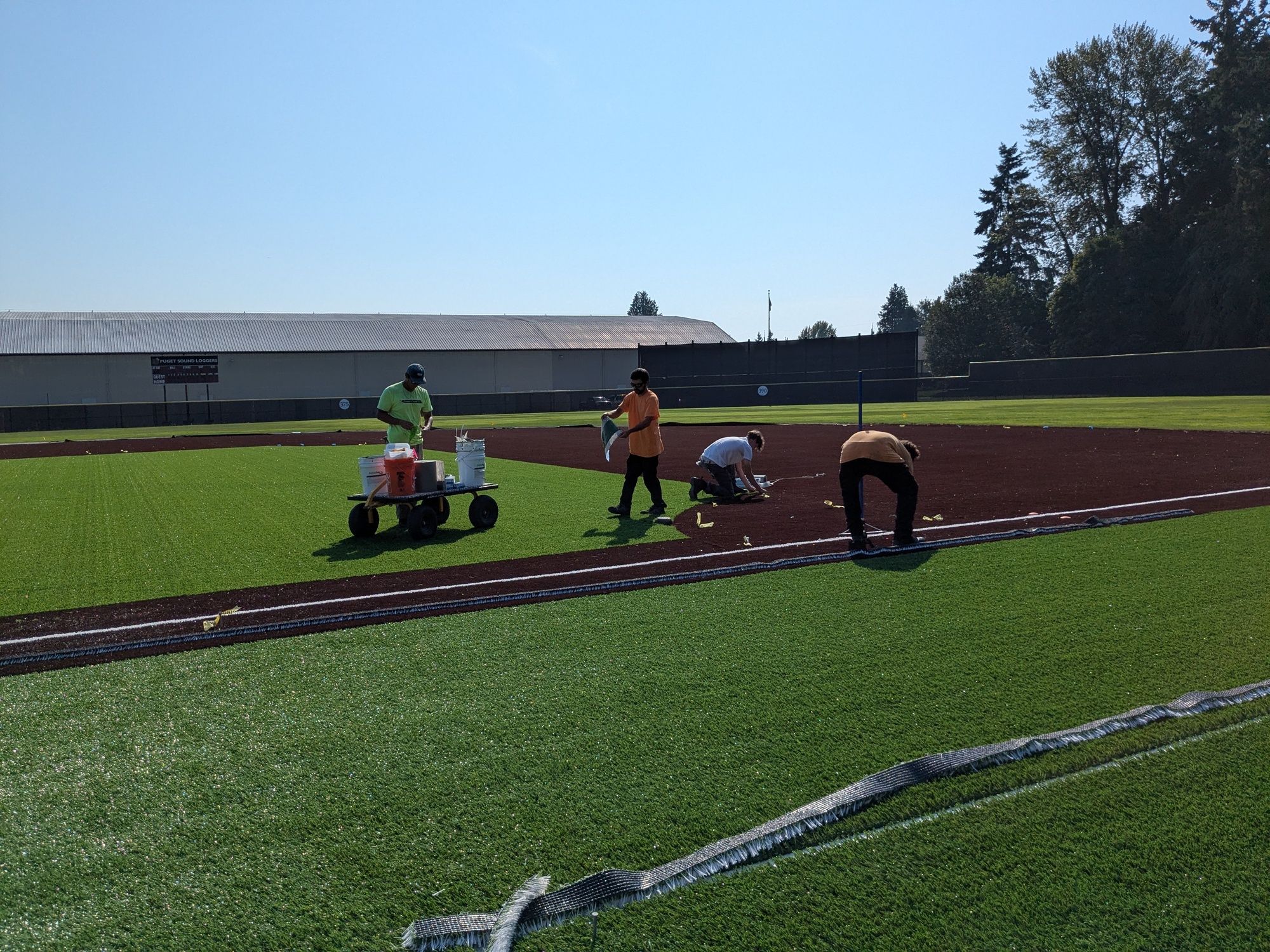 Workers put the finishing touches on the synthetic turf installation