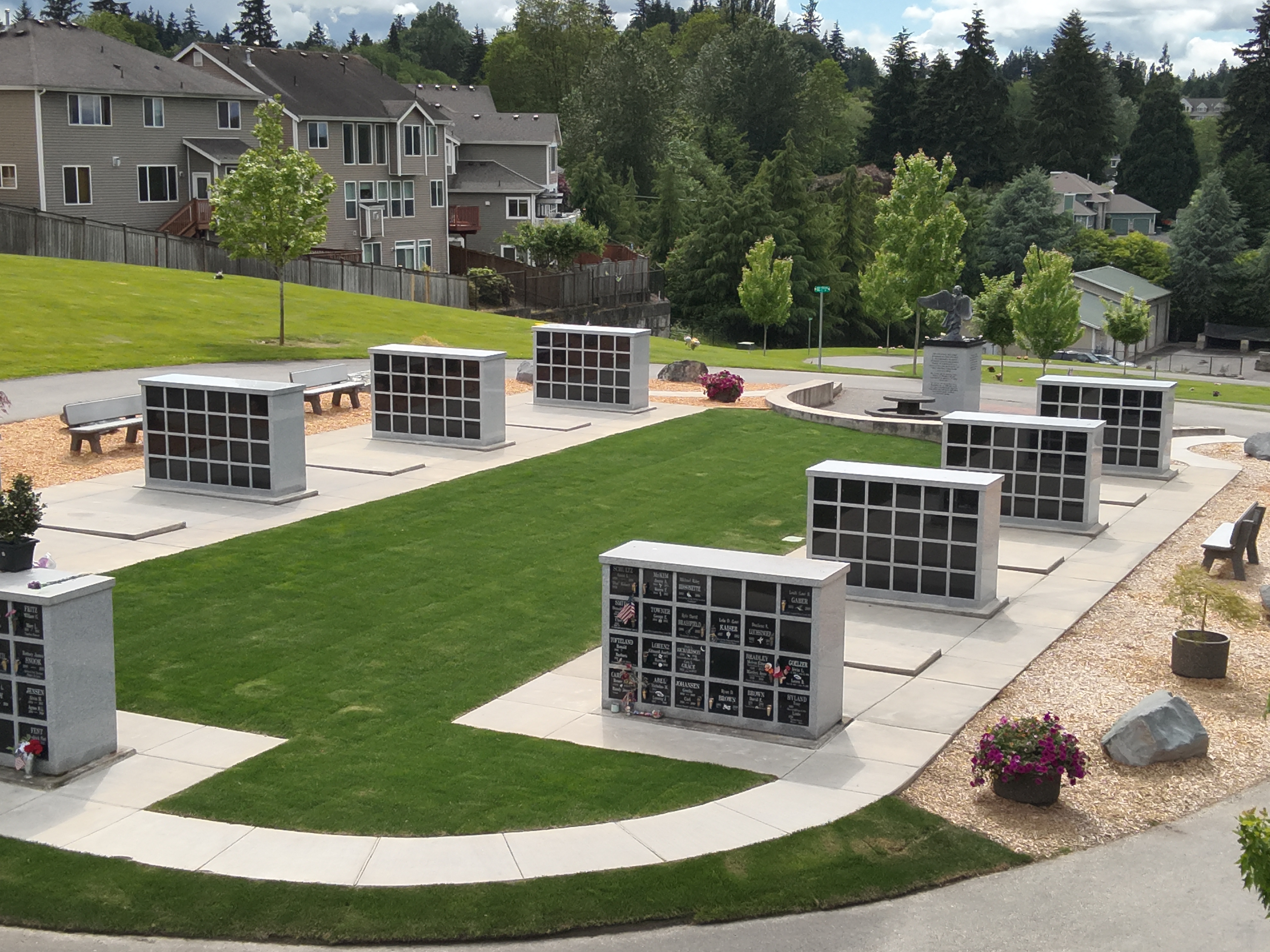 A lawn lies between the two internment rows with a minimalist landscape and benches flanking each row