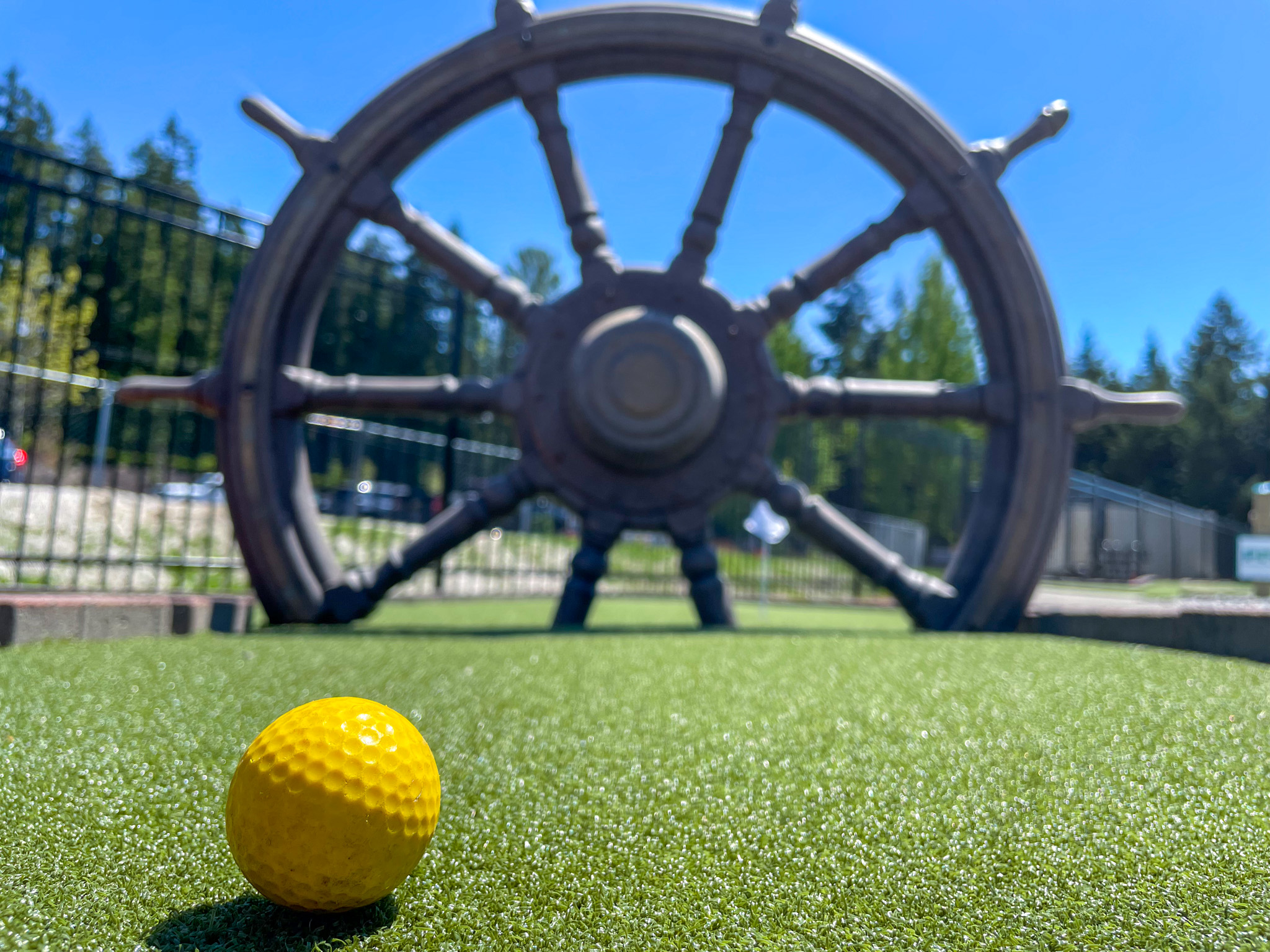 A ship wheel replica is set into the course green with its spokes splitting the width of the green into three passages