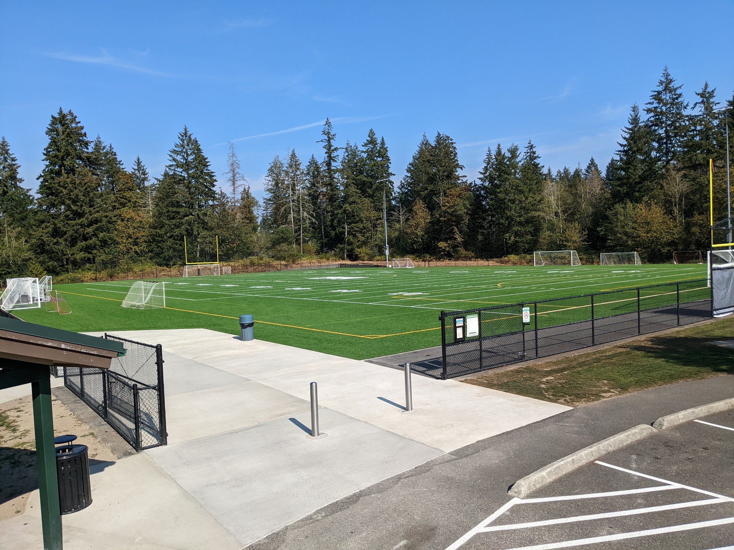 A large gate opens onto a concrete pad at one corner of the field
