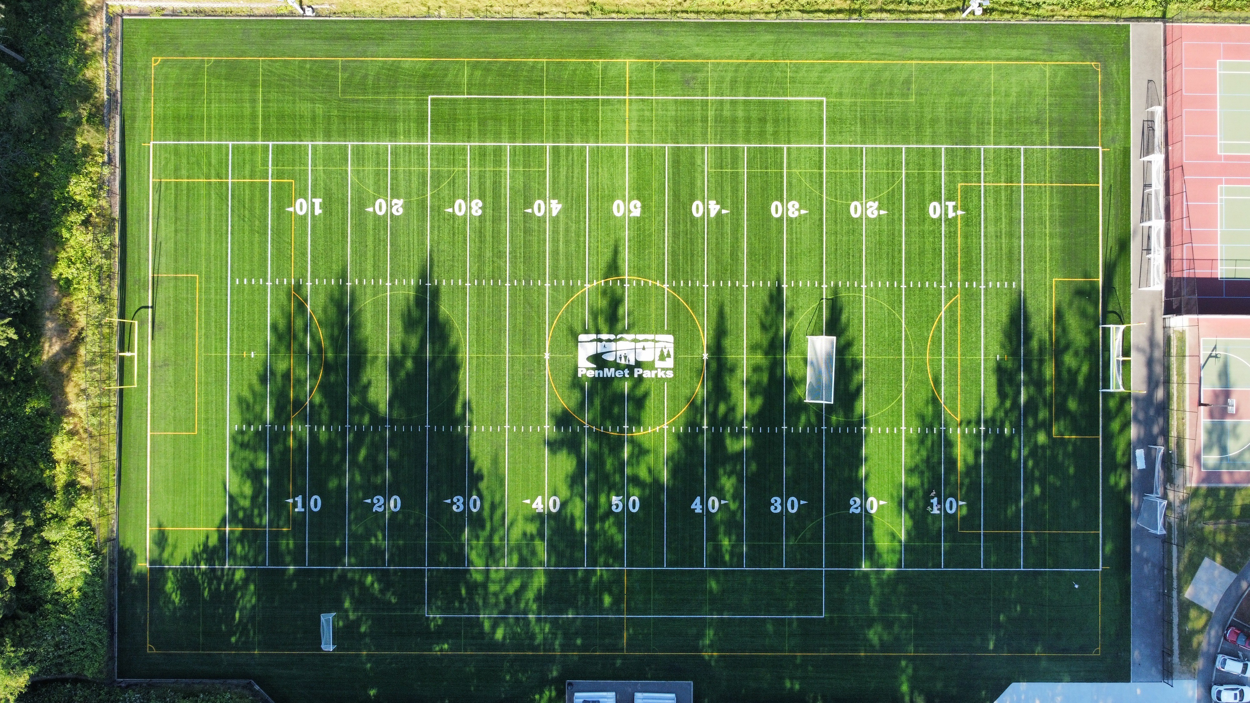 The field includes lines for American football and soccer with the PenMet Parks logo painted at the center